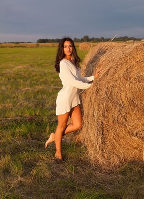 Голая брюнетка на стоге сена в деревенском поле