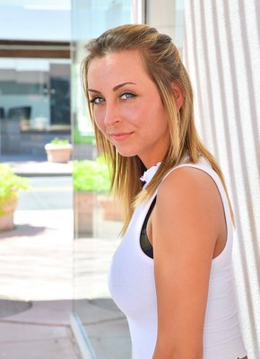 Девушка в джинсовых шортах и майке позирует на улице